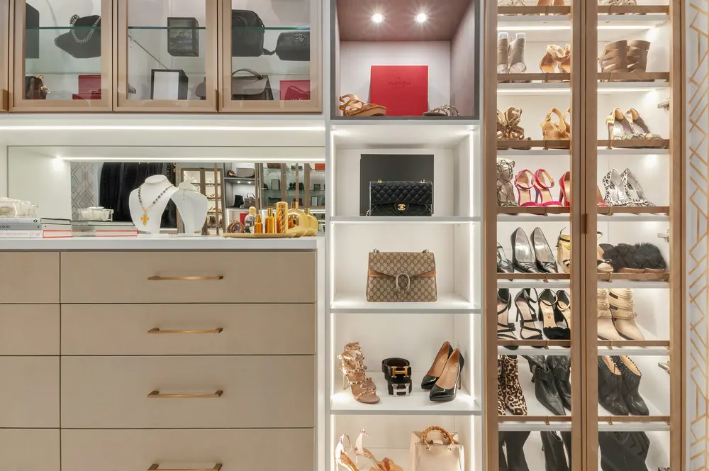 Closet com prateleiras iluminadas, gavetas e sapatos organizados